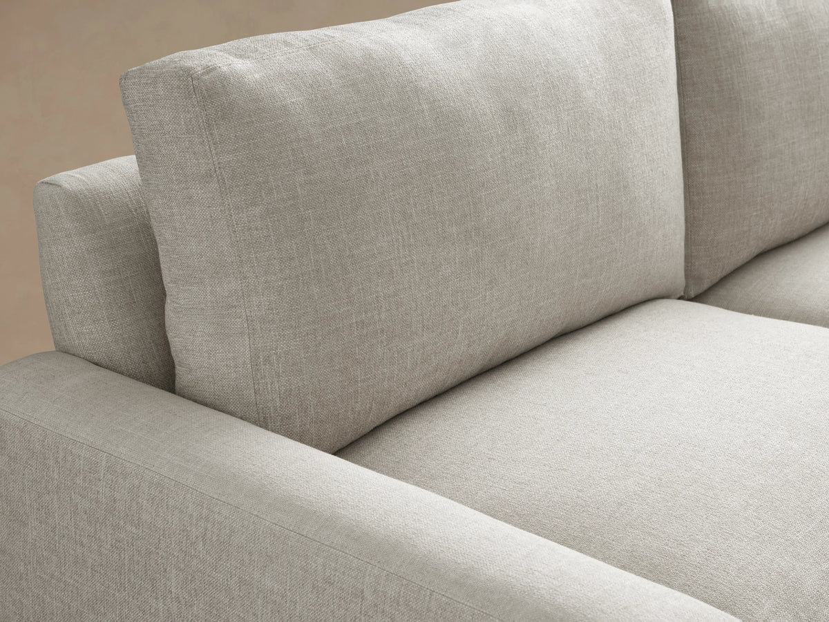 Light gray Remington Sofa with two plump seat and back cushions, squared arms, shown front-facing on a wood floor.