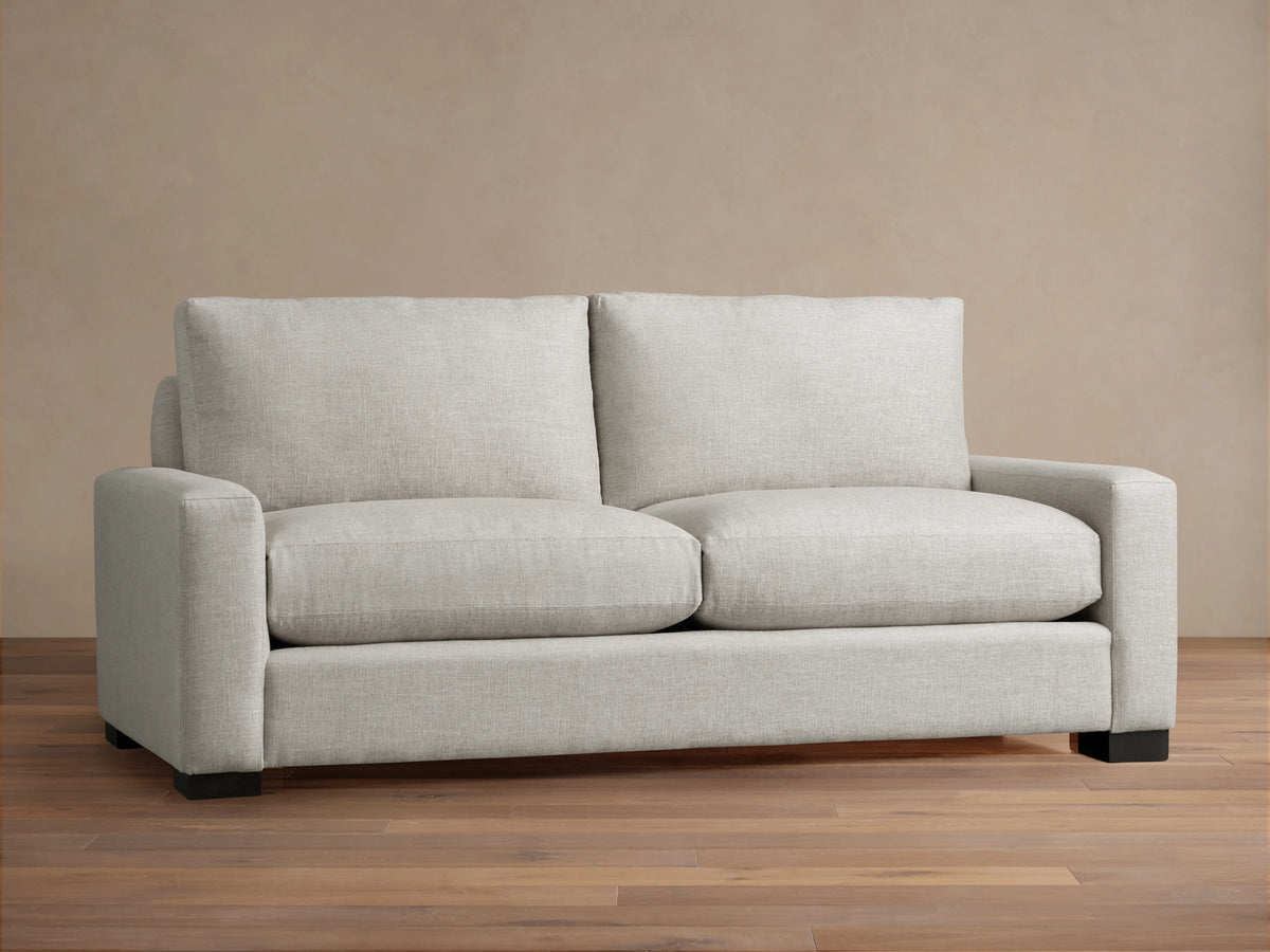 Close-up of a light beige Remington Sofa showing plush back cushions, seat cushion, and armrest with woven fabric texture.