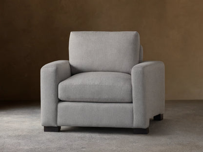 Front view of a light gray Remington Chair with thick, straight arms, plush seat and back cushions, and dark rectangular feet.