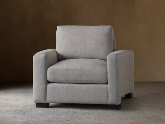 Front view of a light gray Remington Chair with thick, straight arms, plush seat and back cushions, and dark rectangular feet.