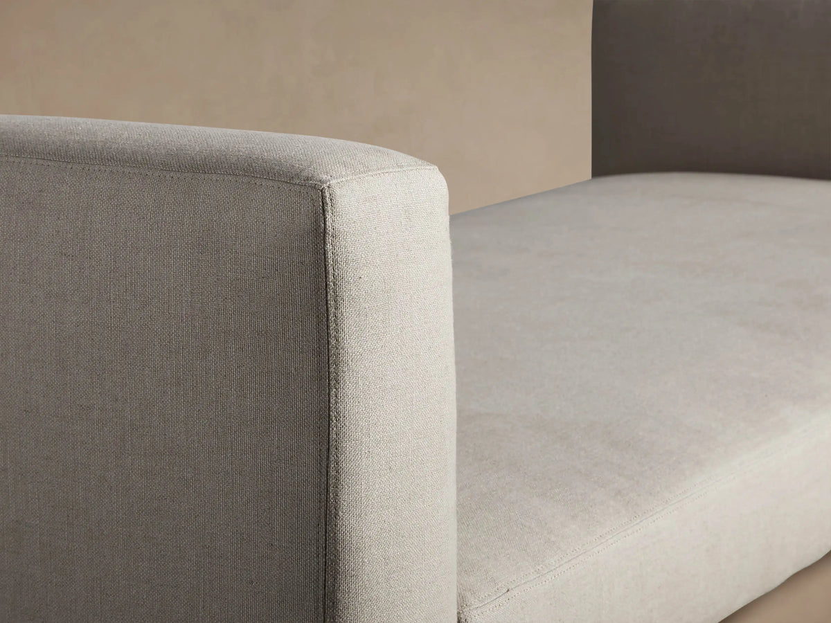 Light beige Remington Trundle Sleeper Daybed with short armrests, visible trundle base, on a wooden floor against a tan wall.