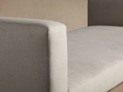 Light beige Remington Trundle Sleeper Daybed with short armrests, visible trundle base, on a wooden floor against a tan wall.