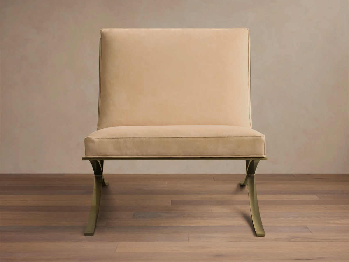 Front view of a light beige Moxie Leather Chair with a rectangular back, stitched seat cushion, and sculptural gold-toned metal legs.