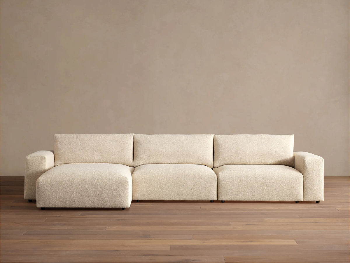 Keegan Tailored Three-Piece Chaise Sectional in textured cream fabric. Left-facing chaise, two seats, light brown wall, wood floor.