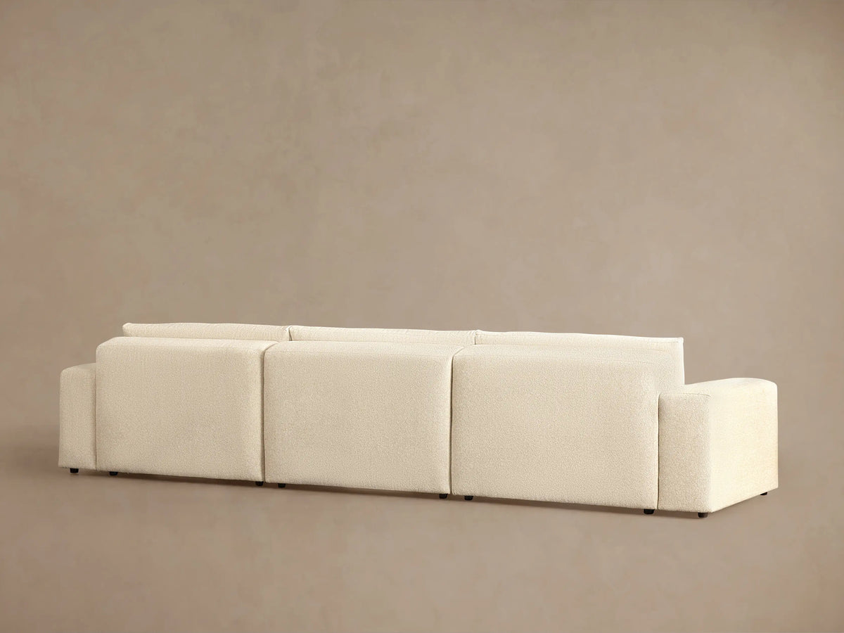 Close-up of the Keegan Tailored Chaise Sectional, showing light beige textured fabric on the back and seat cushions.