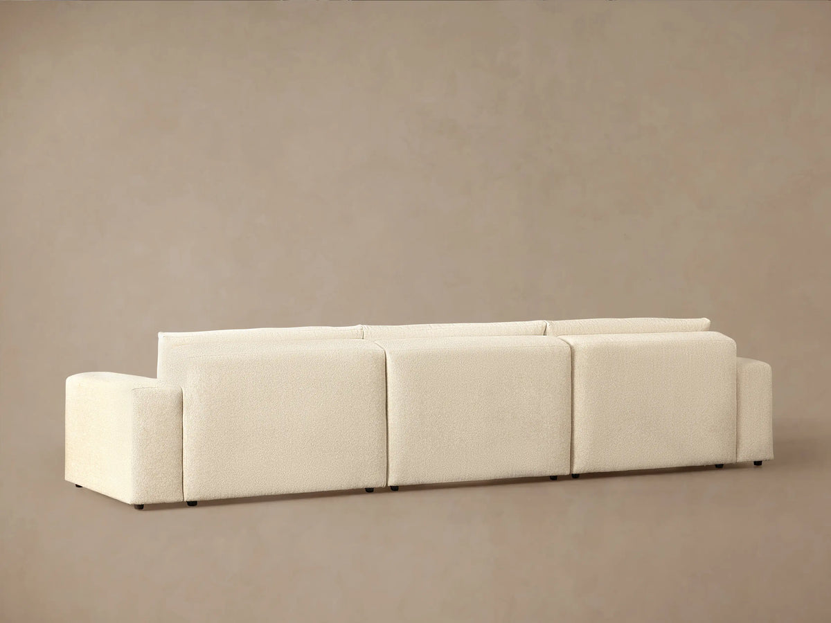 Close-up of Keegan Tailored Chaise Sectional, showing plush, light cream textured fabric back cushions and armrest, angled.