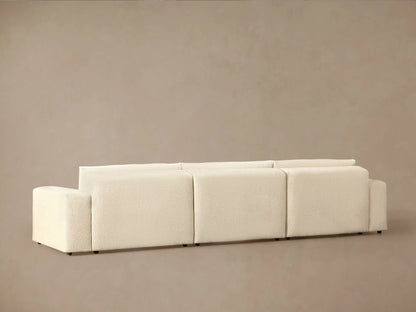 Close-up of Keegan Tailored Chaise Sectional, showing plush, light cream textured fabric back cushions and armrest, angled.