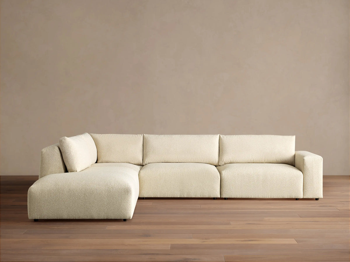 Off-white textured Keegan Tailored Four-Piece Bumper Sectional, L-shaped, with a left chaise, against a neutral wall.
