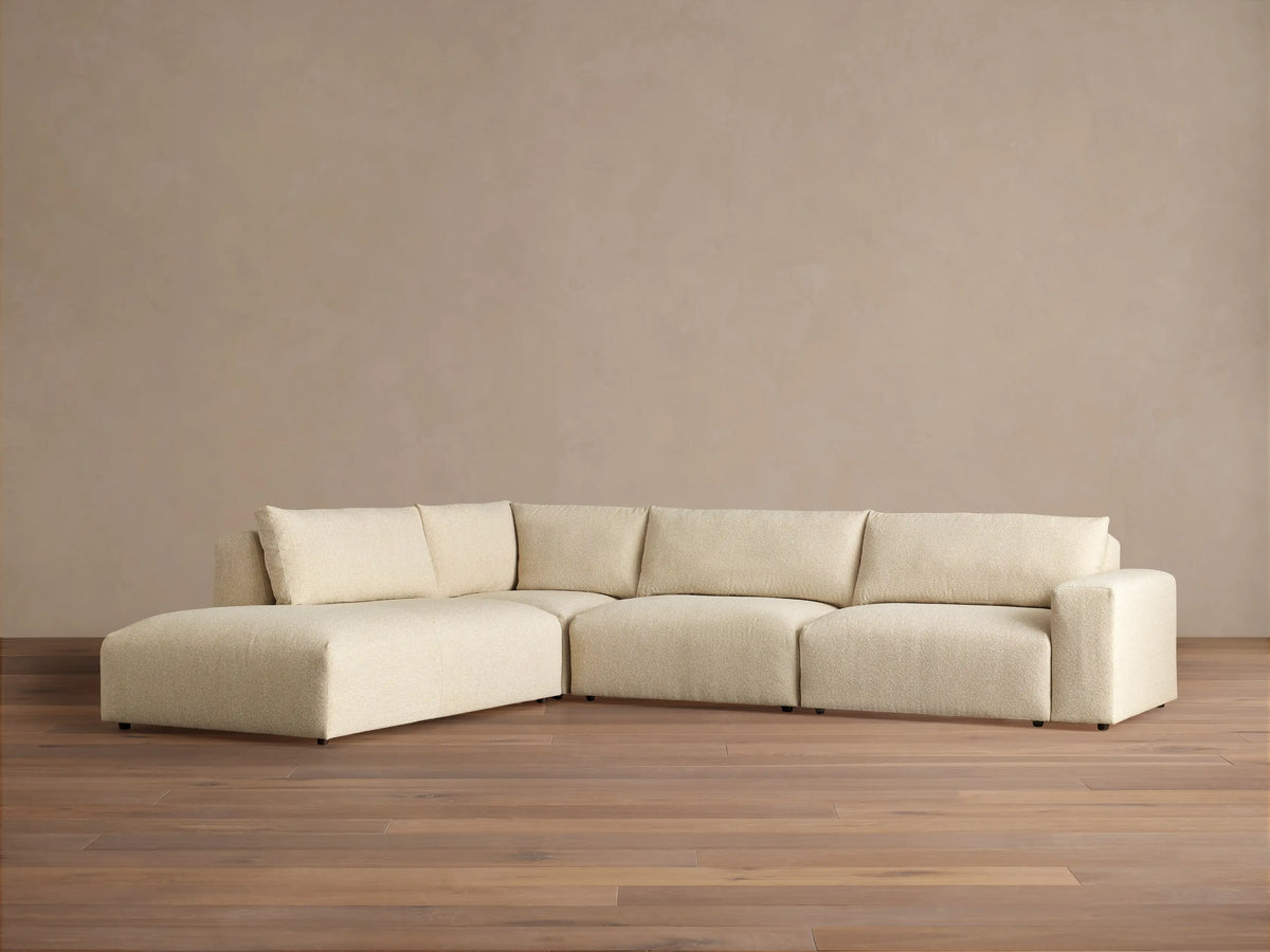 Off-white textured Keegan Tailored Four-Piece Bumper Sectional, L-shaped, with a left chaise, against a neutral wall.
