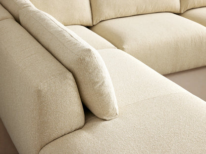 Keegan cream L-shaped 4-piece bumper sectional sofa on a wooden floor against a warm beige wall.