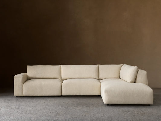 Off-white textured Keegan Tailored Four-Piece Bumper Sectional, L-shaped, with a left chaise, against a neutral wall.