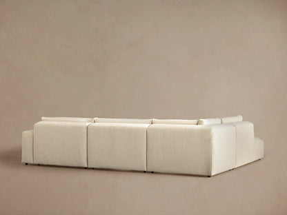 Angled view of a cream-colored Keegan Tailored Four-Piece Bumper Sectional, highlighting its textured fabric, plush backrest, and seat cushion.