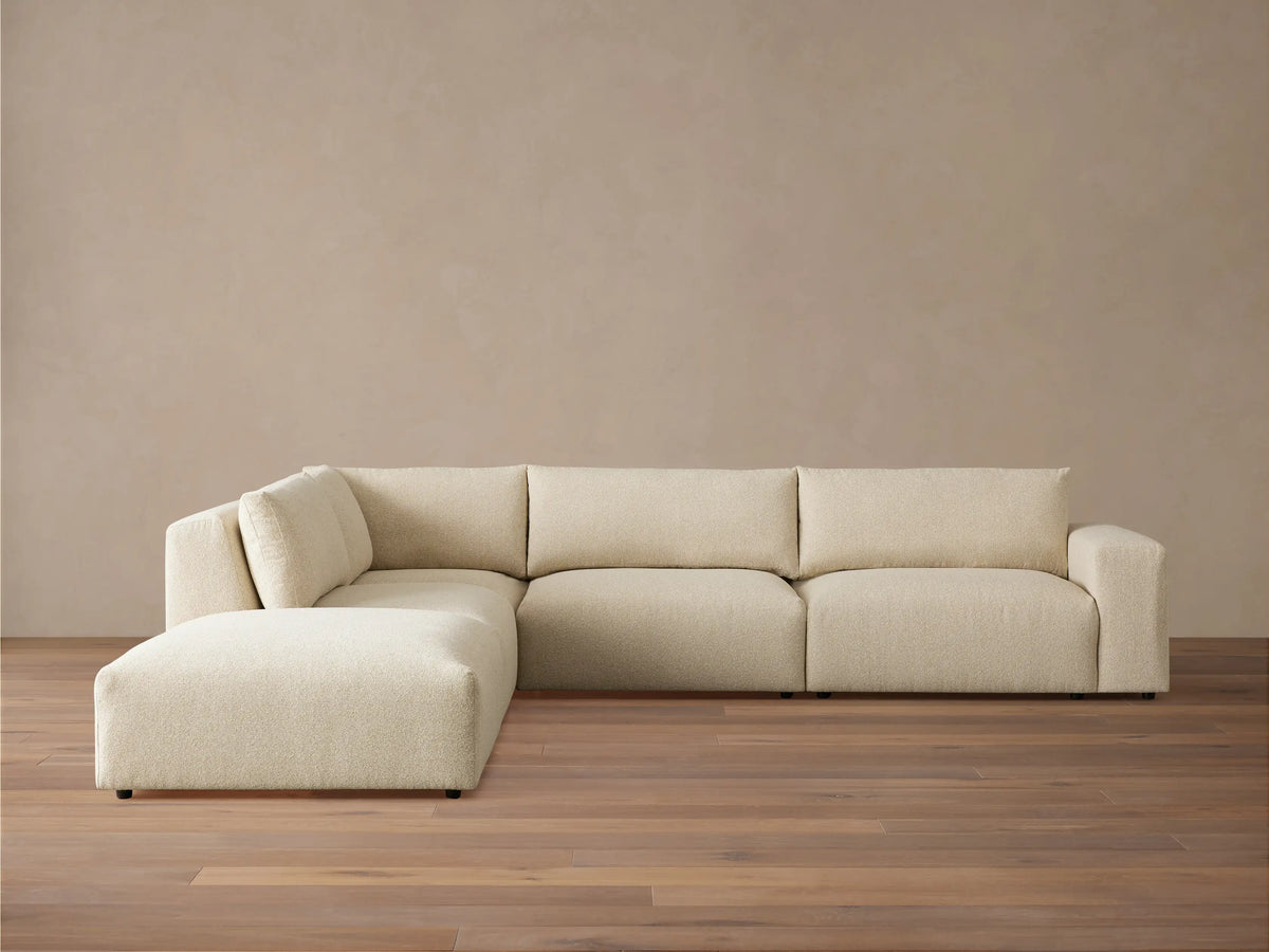 Light beige textured Keegan Tailored Five-Piece Sectional sofa with L-shape, chaise on left, on a wood floor.