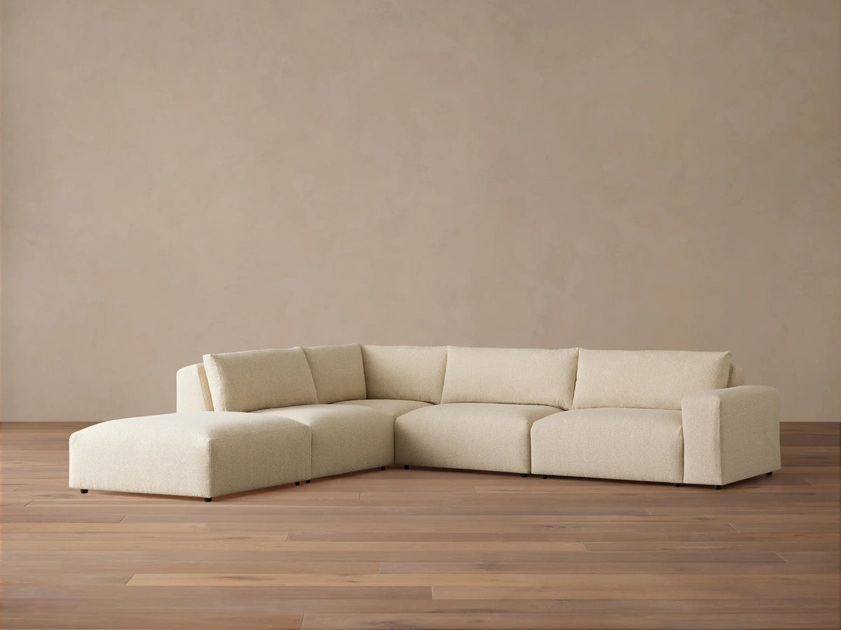 Light beige textured Keegan Tailored Five-Piece Sectional sofa with L-shape, chaise on left, on a wood floor.