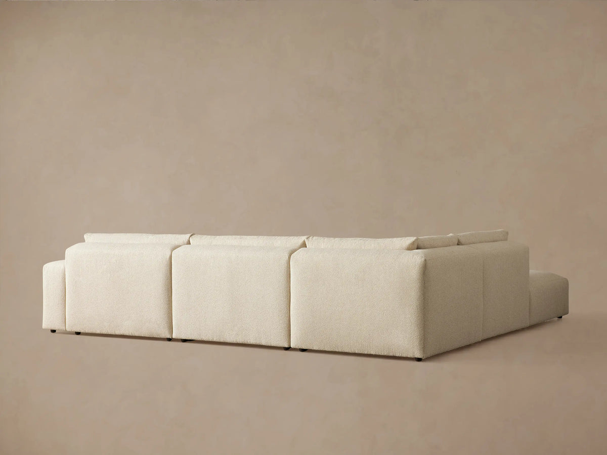 Close-up of a light beige Keegan Tailored Five-Piece Sectional. The image shows the textured fabric on its plush seat and back cushions from an elevated view.
