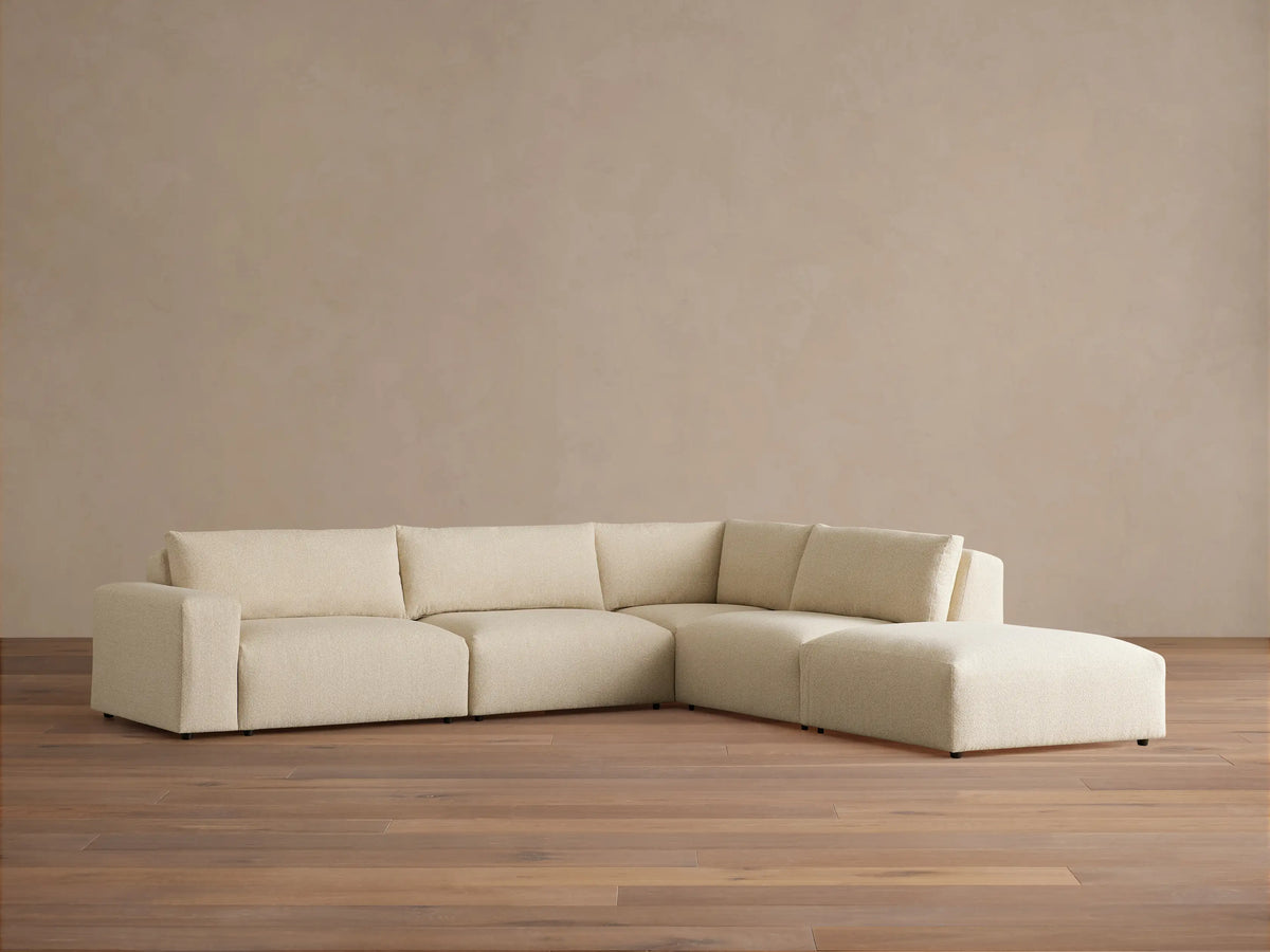 Keegan Tailored Five-Piece Sectional in light beige textured fabric, L-shaped, against a tan wall on wood floor.