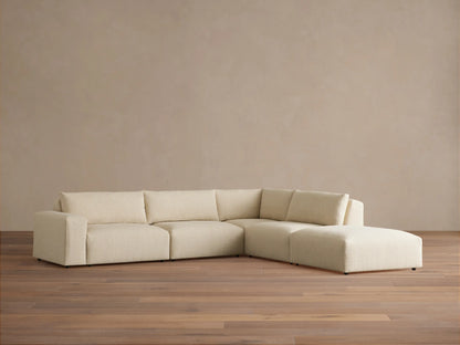 Keegan Tailored Five-Piece Sectional in light beige textured fabric, L-shaped, against a tan wall on wood floor.