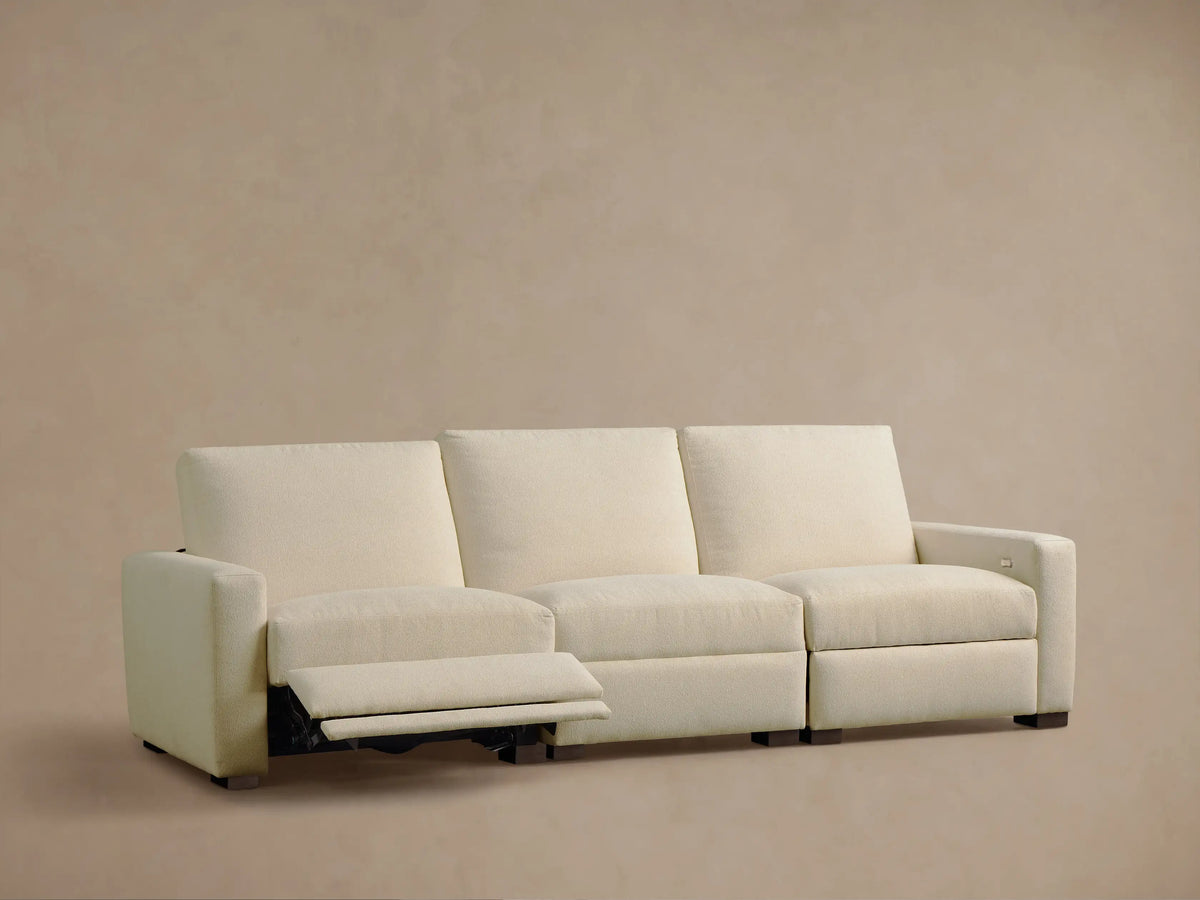 Front view of the Cream Remington Three-Piece Motion Sofa, with the leftmost section reclined and footrest extended.