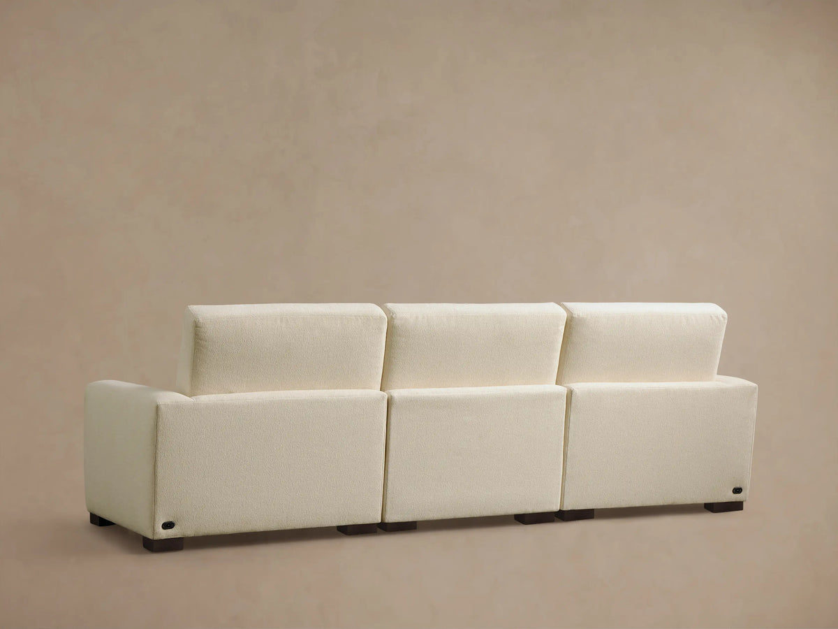 Close-up of the cream Remington Three-Piece Motion Sofa's textured armrest with a silver two-button power recline control.