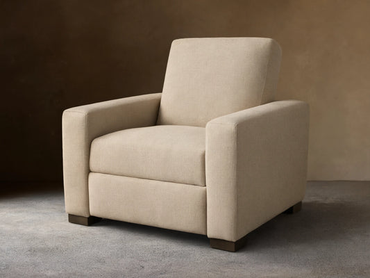 Front-quarter view of the light beige Remington Motion Recliner with square arms and dark block feet.