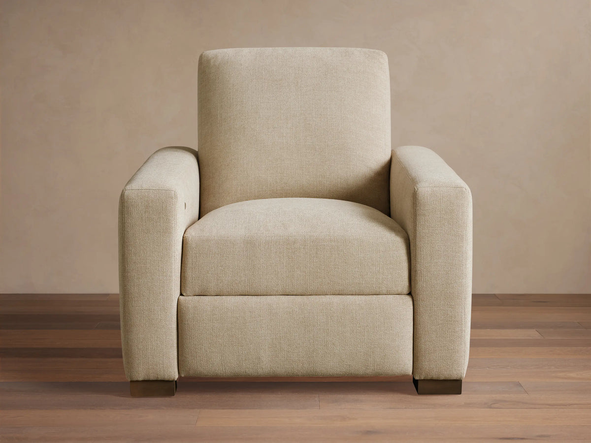 Front-quarter view of the light beige Remington Motion Recliner with square arms and dark block feet.