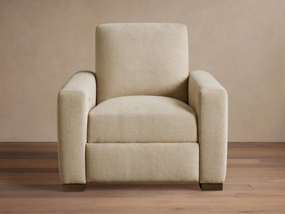 Front-quarter view of the light beige Remington Motion Recliner with square arms and dark block feet.