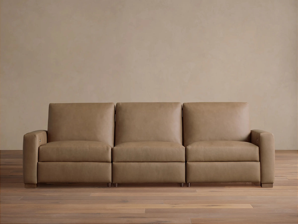 Remington Three-Piece Motion Sofa in tan leather, featuring clean lines and square arms, sits centered on a wood floor.