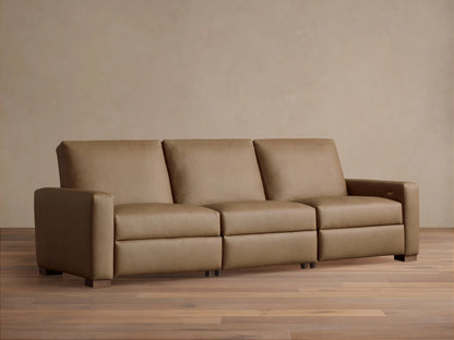 Remington Three-Piece Motion Sofa in tan leather, featuring clean lines and square arms, sits centered on a wood floor.