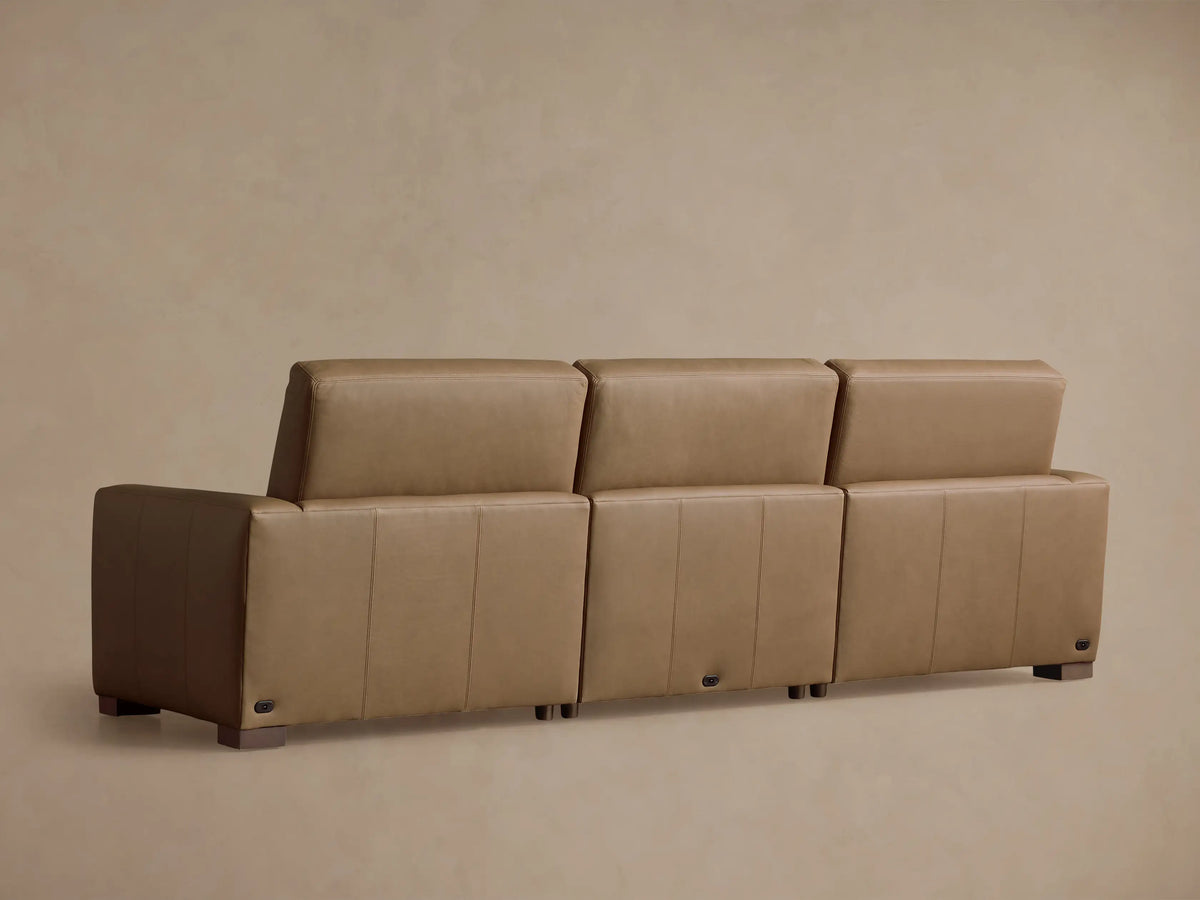 Close-up of a tan leather Remington Motion Sofa, showing smooth cushions, visible stitching, and a partially reclined footrest.
