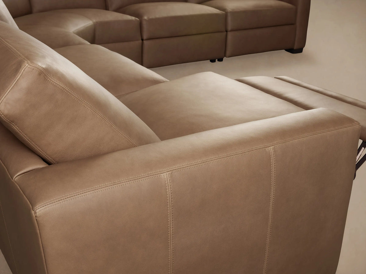 Remington Leather Sectional close-up: brown leather backrest, seat, and silver two-button power recliner control.