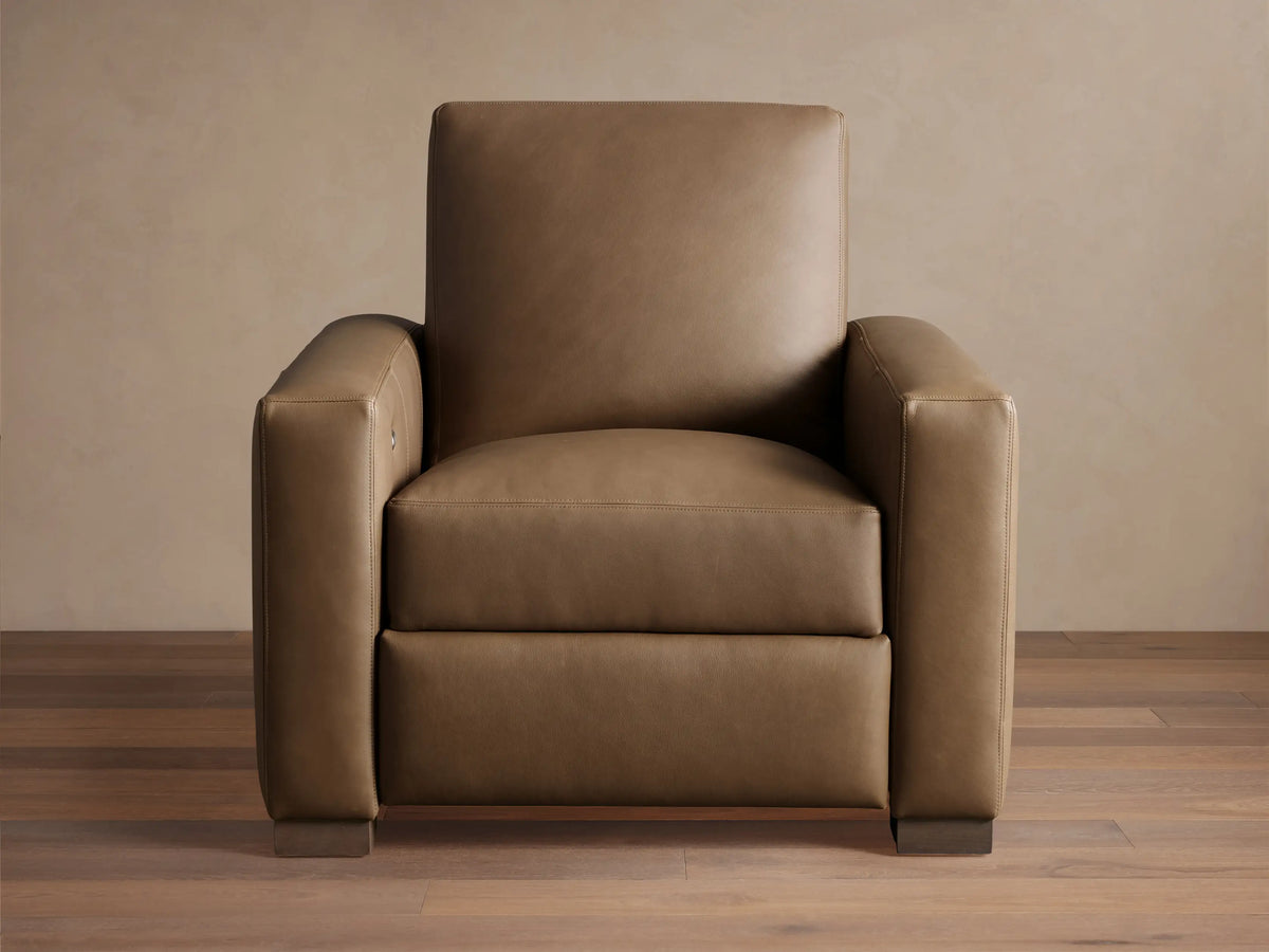 Light brown leather Remington Motion Recliner, a modern armchair with wide arms, seen from the front on wood floor.