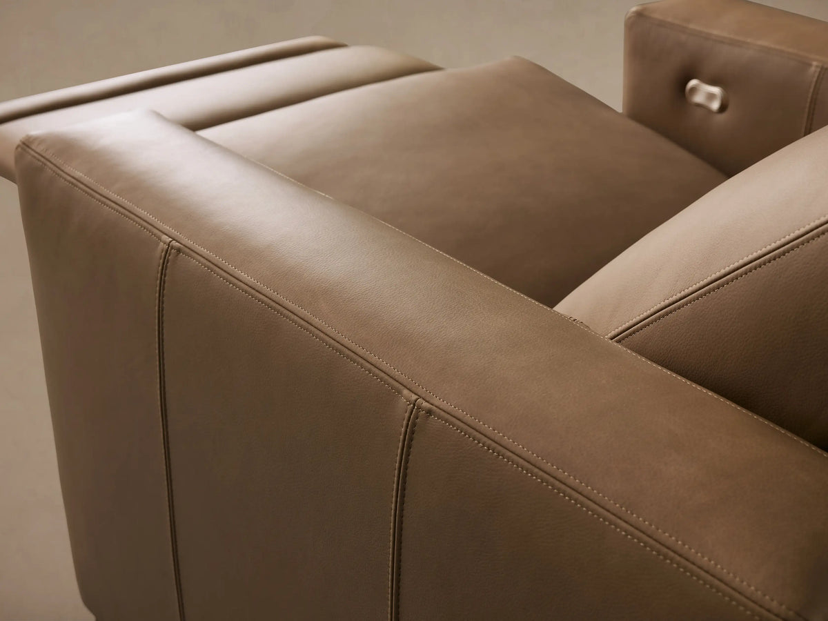 Close-up of Remington Leather Motion Recliner in tan leather, showing detailed stitching and a metallic power recline button.