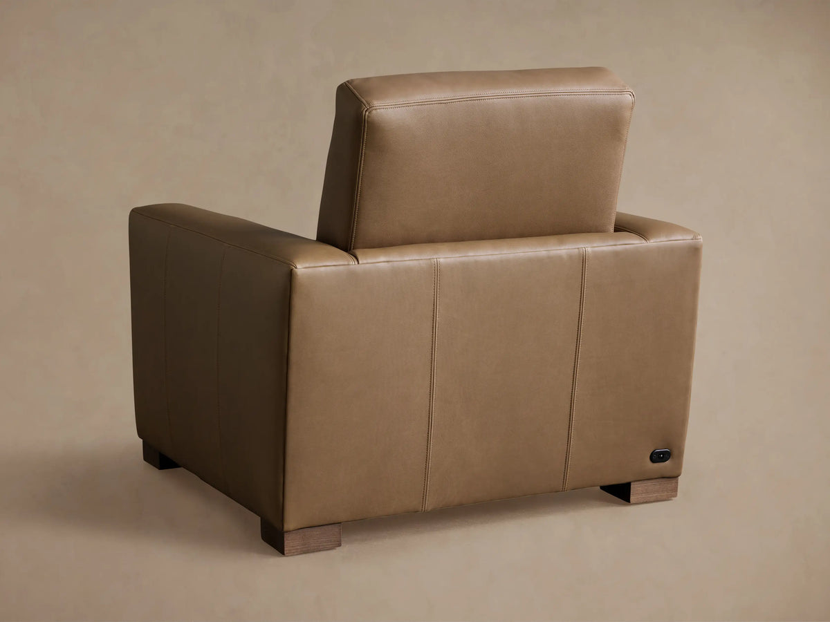Close-up of Remington Leather Motion Recliner in warm brown, highlighting detailed stitching on armrest and back.
