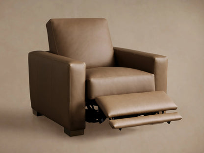 3/4 rear view of a tan leather Remington Motion Recliner with clean stitching, power port, and dark wood block feet.