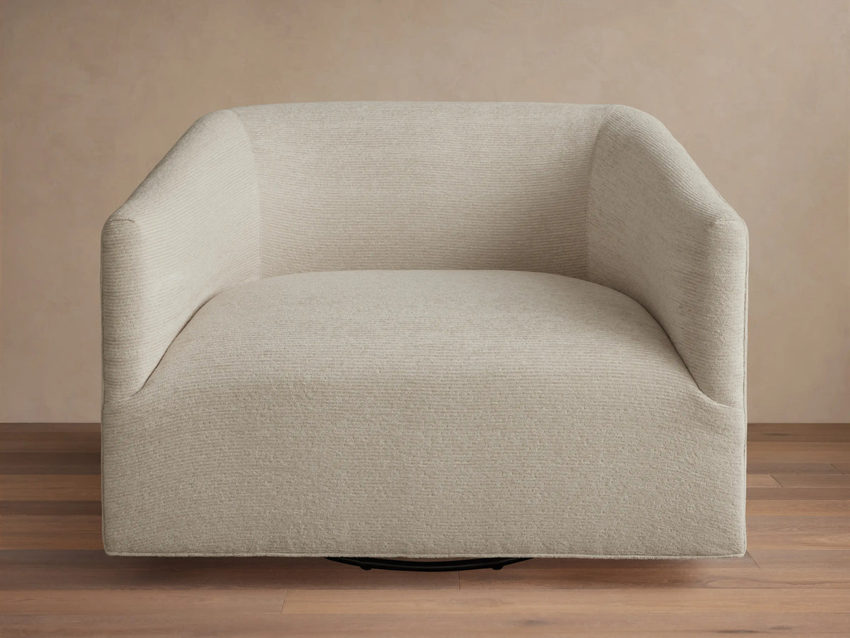 Oversized Ellison Swivel Chair, upholstered in light beige textured fabric, with curved arms & a visible black swivel base.