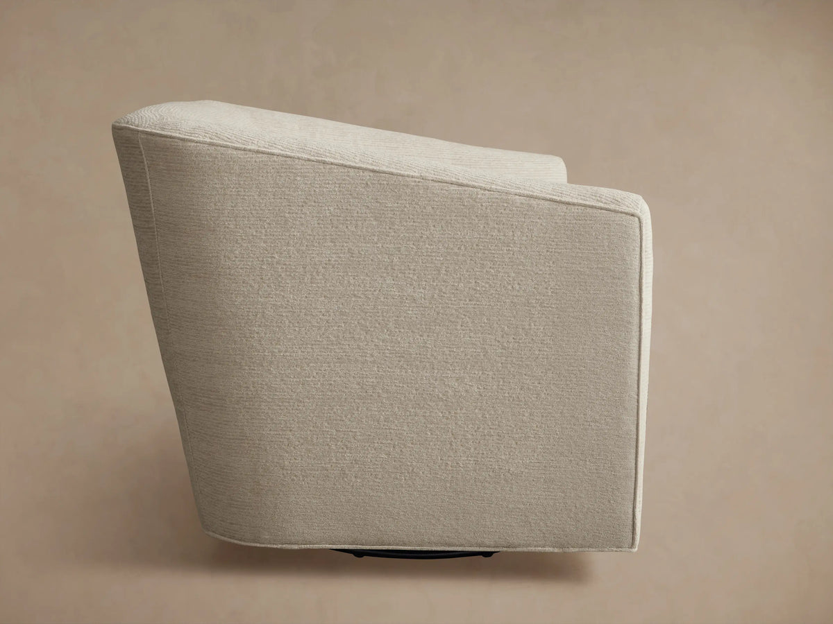 Ellison Oversized Swivel Chair, upholstered in light beige textured fabric, viewed from the back-side, showing its curved design.