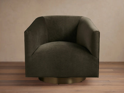 Dark brown Ellison Metal Plinth Swivel Chair with a rounded, cushioned backrest and armrests, on a brass-toned swivel base, against a wooden floor.