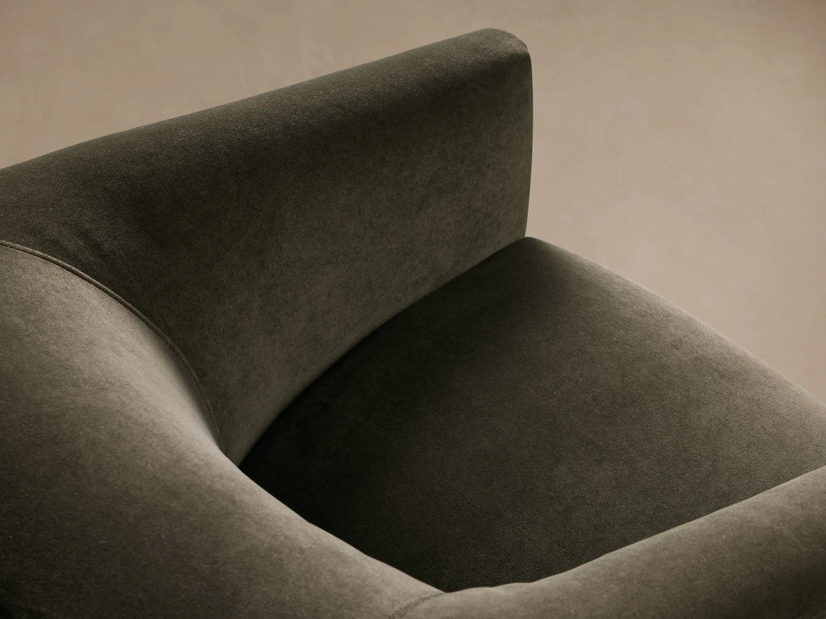 Ellison Metal Plinth Swivel Chair in dark fabric, featuring a curved back and wide arms on a round metal base, shown on hardwood floor.
