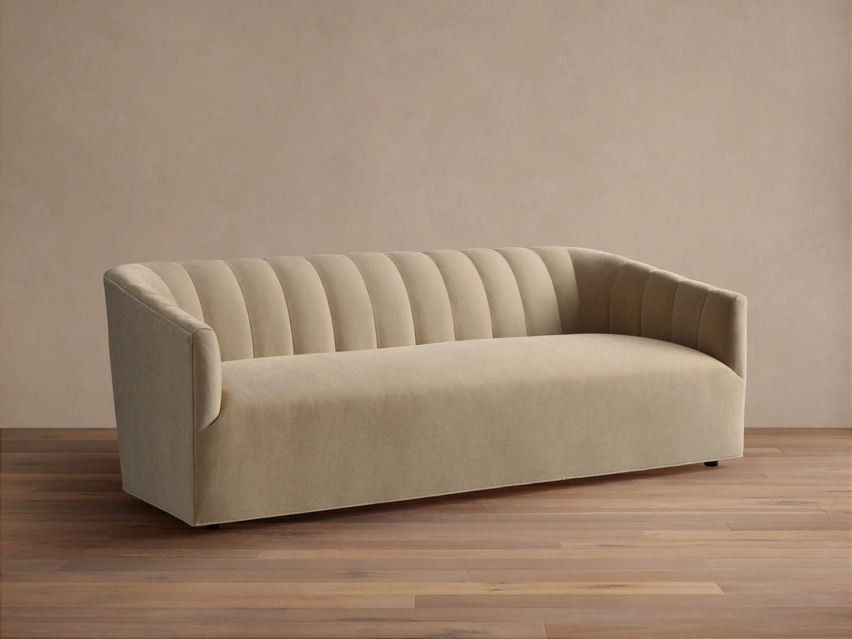 Pale tan Ellison Channel-Stitched Sofa, front view, with vertical channels on backrest & inner arms, on wood floor against light wall.