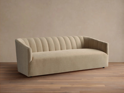 Pale tan Ellison Channel-Stitched Sofa, front view, with vertical channels on backrest & inner arms, on wood floor against light wall.