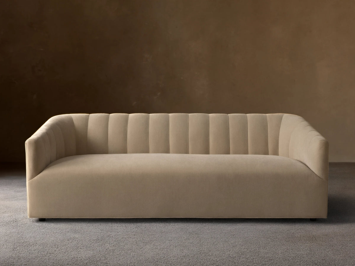 Pale tan Ellison Channel-Stitched Sofa, front view, with vertical channels on backrest & inner arms, on wood floor against light wall.