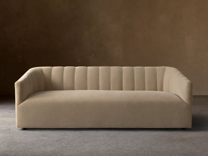 Pale tan Ellison Channel-Stitched Sofa, front view, with vertical channels on backrest & inner arms, on wood floor against light wall.