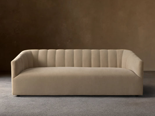 Pale tan Ellison Channel-Stitched Sofa, front view, with vertical channels on backrest & inner arms, on wood floor against light wall.