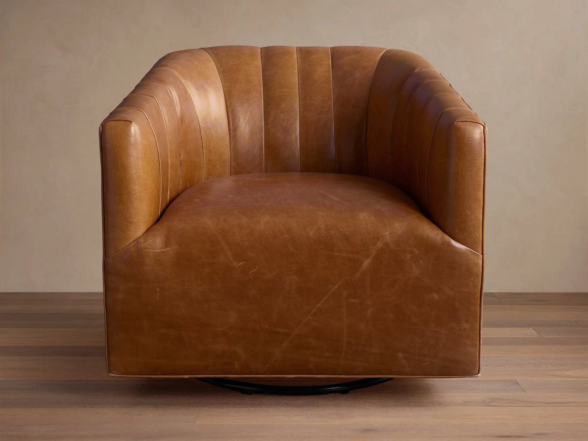 Ellison Leather Channel-Stitched Swivel Glider, a rich brown leather armchair with vertical channel stitching, angled on a wooden floor.