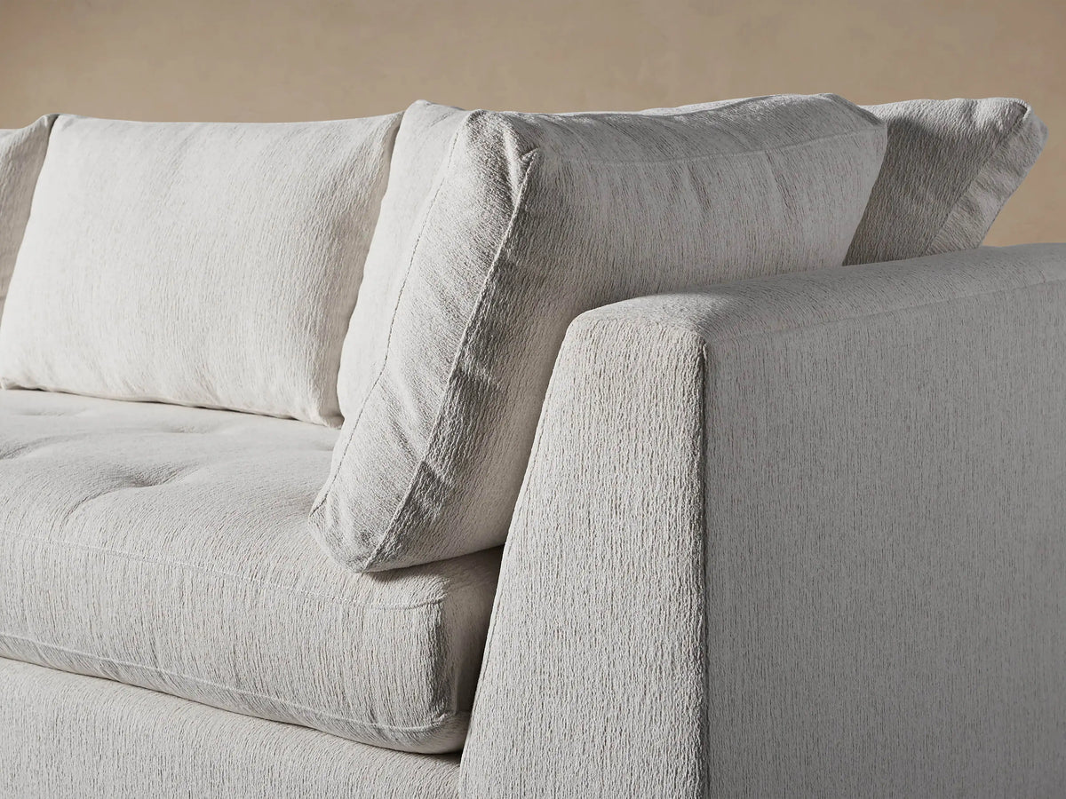 Bryden Two-Piece Daybed Sectional in light fabric, L-shaped with left chaise, dark wood legs on a wood floor.