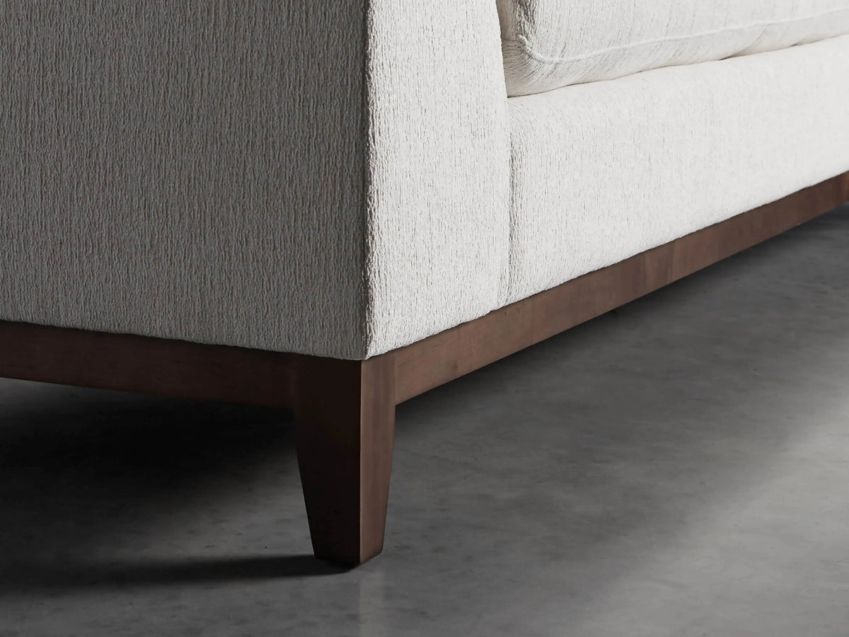 Close-up of Bryden Two-Piece Daybed Sectional. Light neutral textured fabric on armrest, plush back and seat cushions.