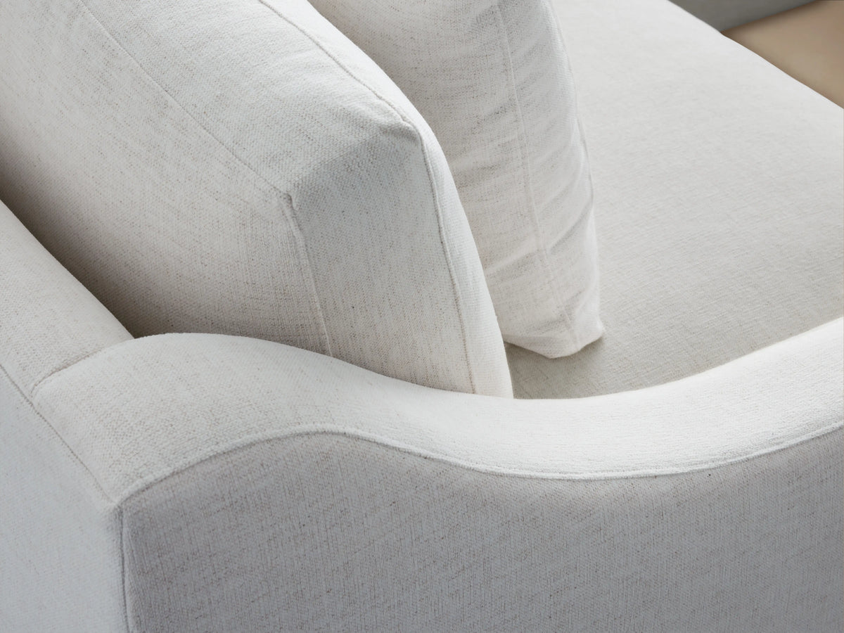 Ashby Two-Piece Sectional in white fabric, showcasing an L-shaped design with plush cushions, on a wooden floor against a beige wall.
