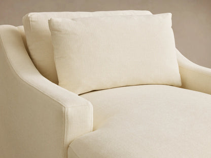 Close-up of the cream Ashby Chaise, showing the textured fabric, a plush back cushion, and a curved armrest.
