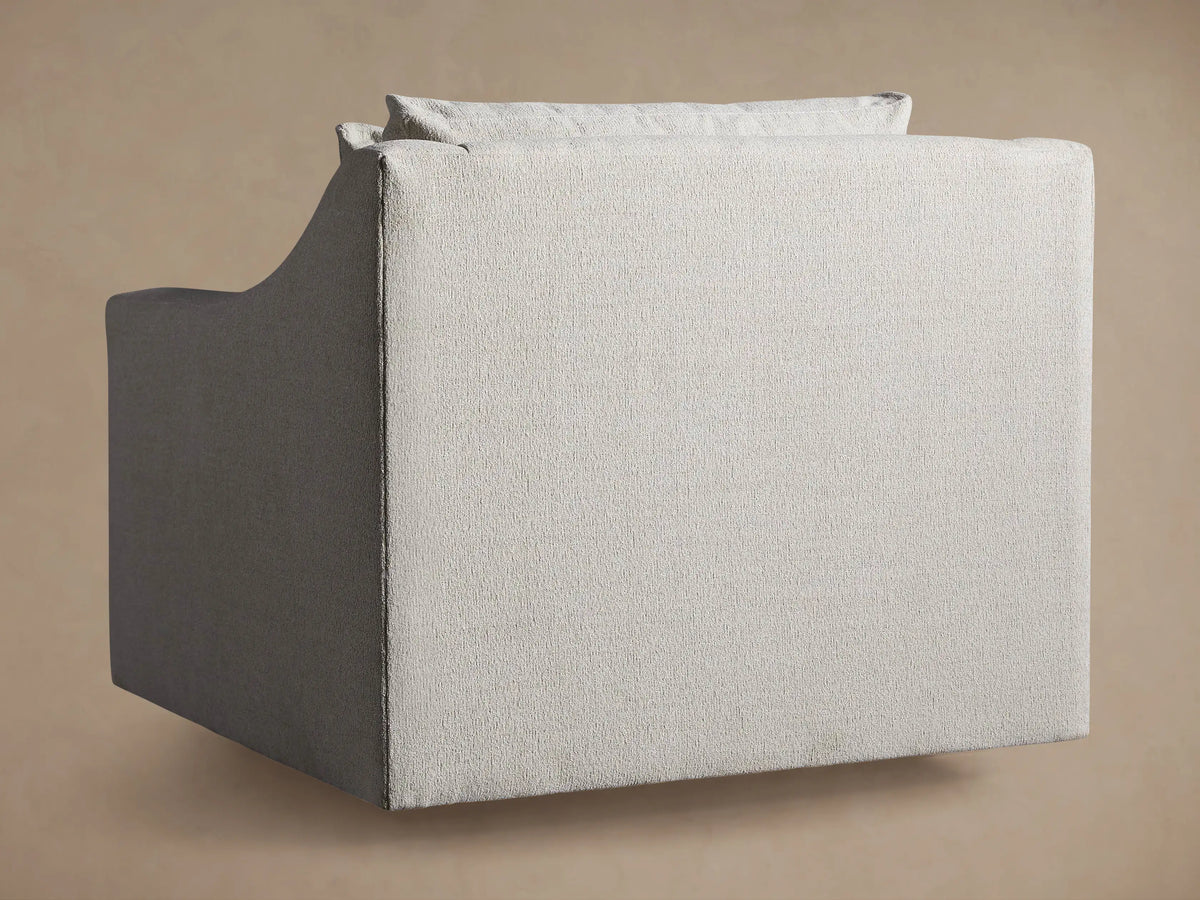 Close-up of Ashby Swivel Chair, showing the curved armrest, seat, and back cushion in light beige textured fabric.