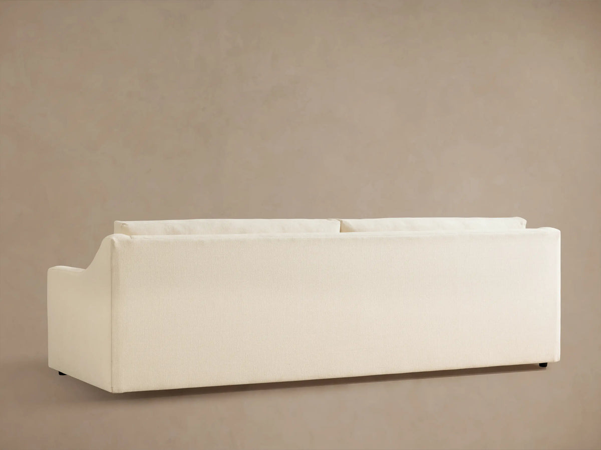Close-up of the cream Ashby Sofa, showing the textured fabric on the armrest, back cushion, and a throw pillow.